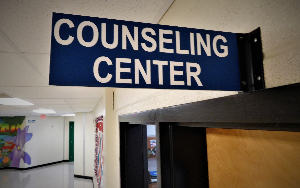   A blue sign that says, Counseling Center, is mounted above a door in a hallway.